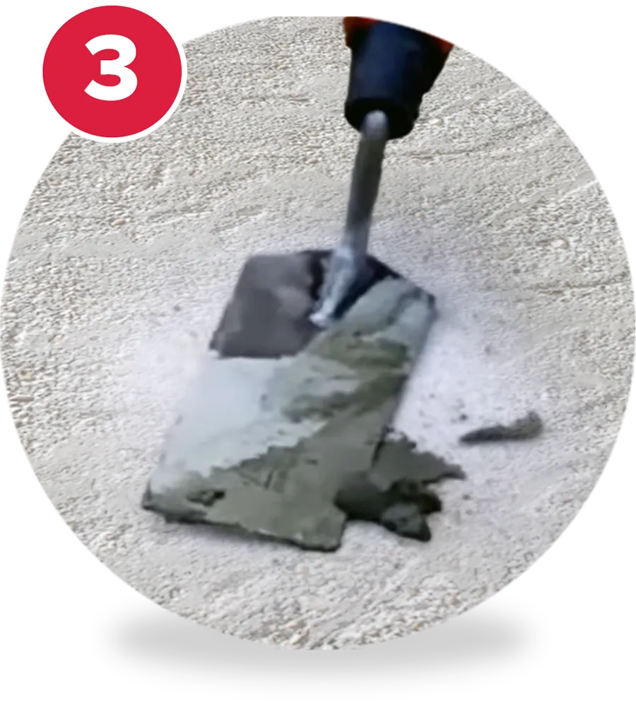 A person using a trowel to on concrete floor, patching a hole.