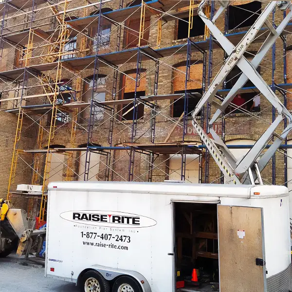 White truck parked in front of building with scaffolding, indicating commercial new commercial foundations.