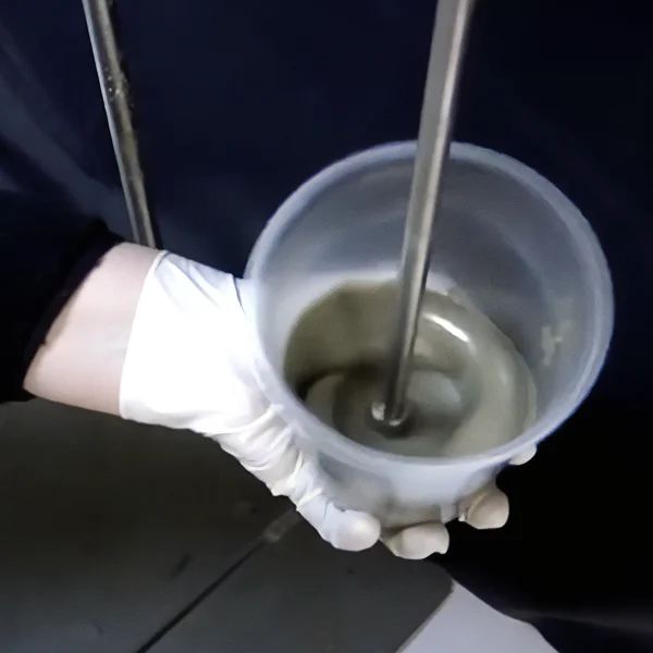 A person holding a cup in their hand, engaged in polyurethane mixing.