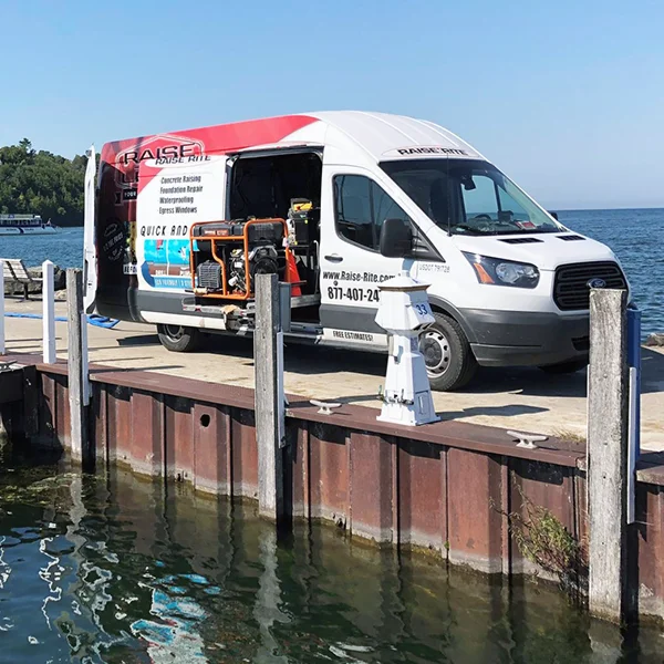 A van parked on a dock by the water's edge.