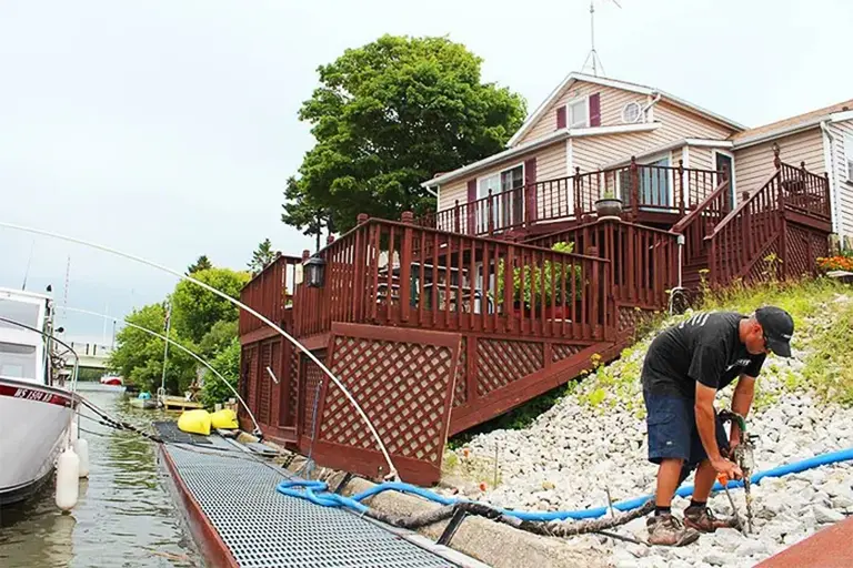 A man working on a boat dock doing Raise Rite Deep Foamjection™ on top of rocks.